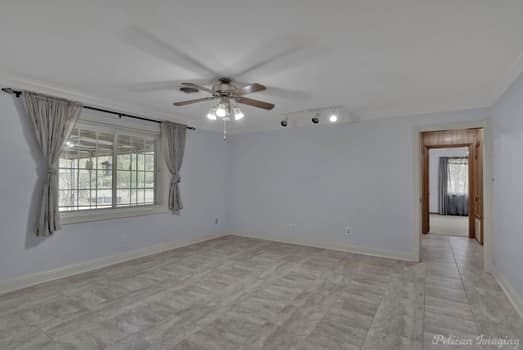 unfurnished room with a healthy amount of sunlight, ceiling fan, and baseboards