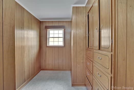 carpeted empty room with wood walls, ornamental molding, and ceiling fan