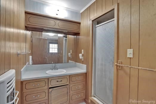 bathroom with wood walls, crown molding, vanity, and toilet