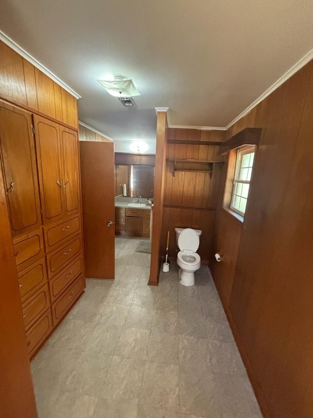 bathroom with visible vents, wood walls, toilet, and crown molding