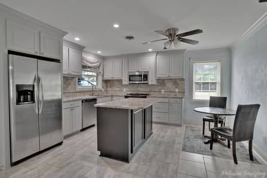 kitchen featuring decorative backsplash, appliances with stainless steel finishes, a center island, light stone countertops, and crown molding