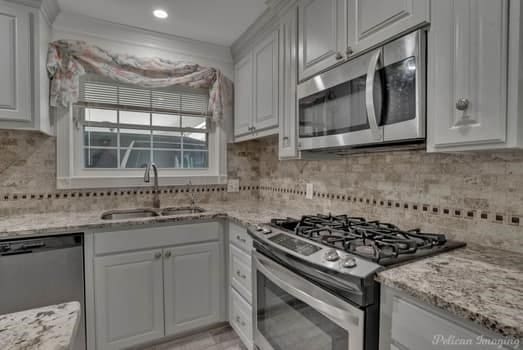 kitchen with appliances with stainless steel finishes, a sink, and white cabinets