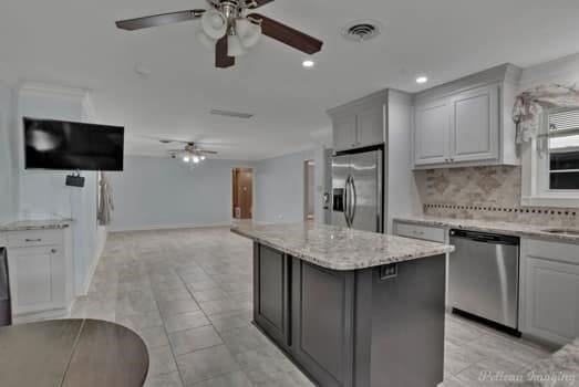 kitchen featuring gray cabinets, visible vents, backsplash, appliances with stainless steel finishes, and a kitchen island