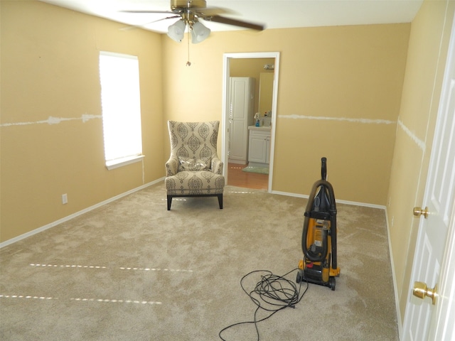 living area with light carpet and ceiling fan