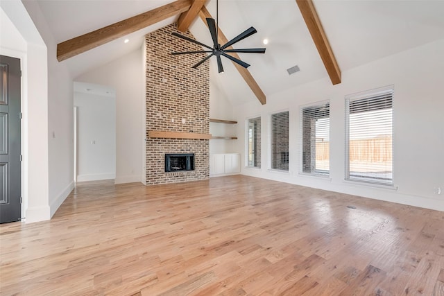 unfurnished living room with a fireplace, high vaulted ceiling, beam ceiling, and ceiling fan