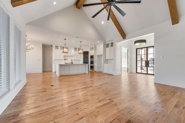 unfurnished living room featuring high vaulted ceiling, light wood-type flooring, beam ceiling, and ceiling fan