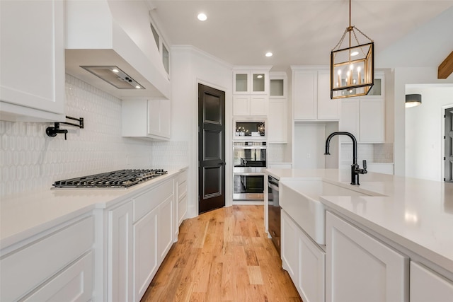 kitchen featuring sink, white cabinets, premium range hood, and stainless steel appliances