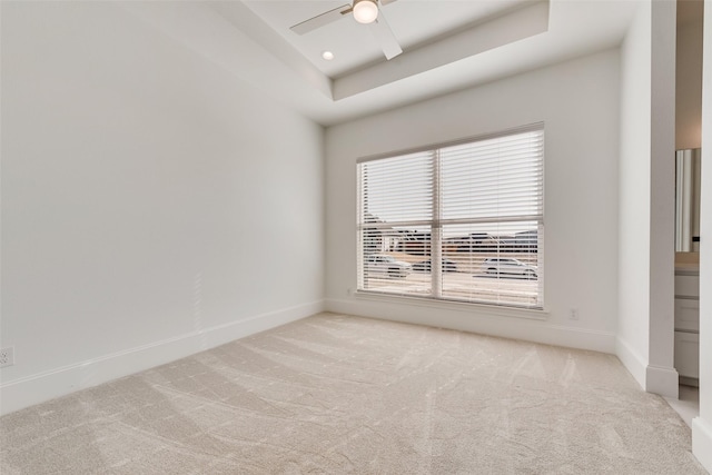 carpeted spare room featuring a raised ceiling and ceiling fan