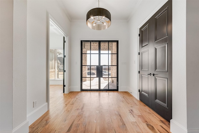 doorway with light wood-type flooring, crown molding, and an inviting chandelier