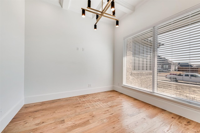 empty room featuring an inviting chandelier, beam ceiling, and light hardwood / wood-style floors