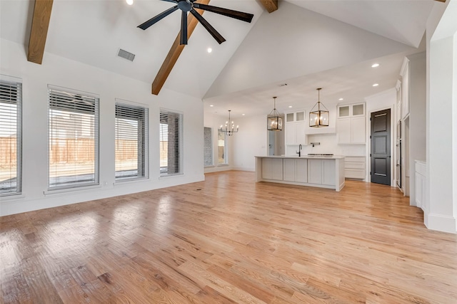 unfurnished living room featuring ceiling fan with notable chandelier, high vaulted ceiling, light wood-type flooring, and beamed ceiling