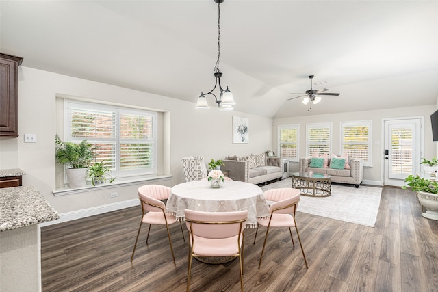 dining area with a healthy amount of sunlight, dark wood-type flooring, ceiling fan with notable chandelier, and vaulted ceiling