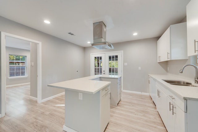 kitchen with light hardwood / wood-style flooring, white cabinets, sink, and a kitchen island