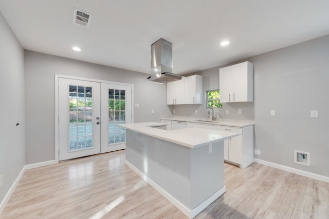 kitchen featuring french doors, a kitchen island, extractor fan, white cabinetry, and light hardwood / wood-style floors