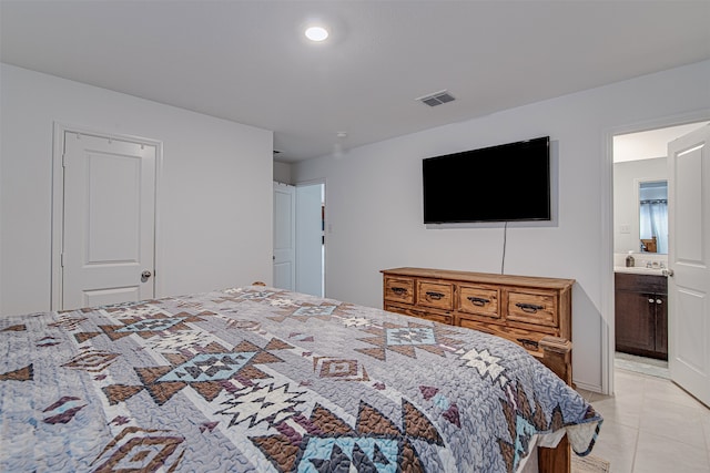 bedroom with ensuite bathroom and light tile patterned floors