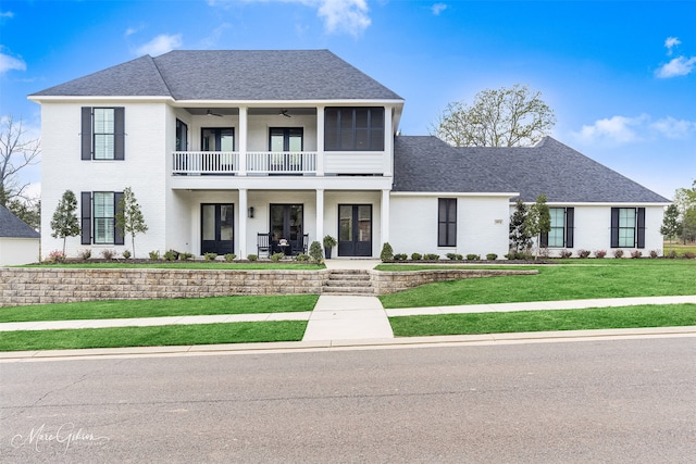 view of front of house with french doors, a balcony, and a front lawn