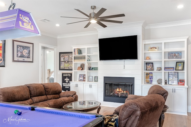 living room with a large fireplace, ornamental molding, light hardwood / wood-style floors, and ceiling fan