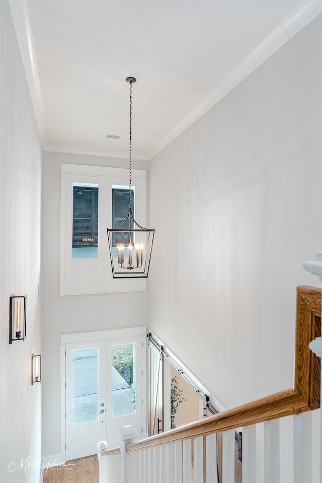 stairway featuring ornamental molding, wood-type flooring, a chandelier, and french doors