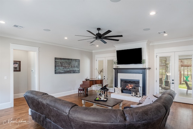 living room featuring french doors, ornamental molding, wood-type flooring, and ceiling fan