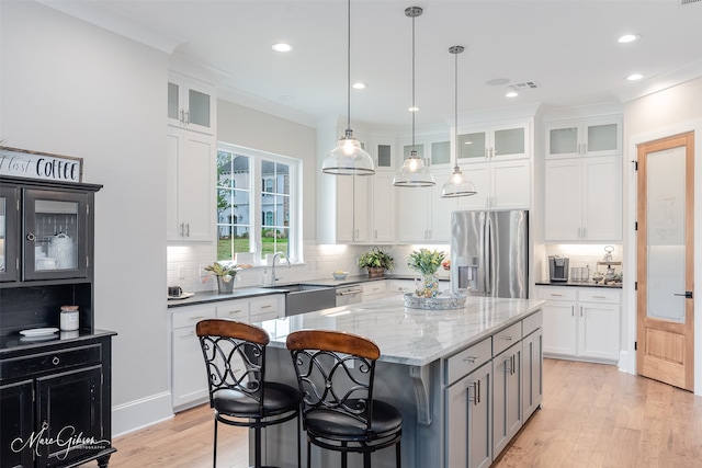 kitchen featuring stainless steel appliances, white cabinetry, a center island, and dark stone countertops