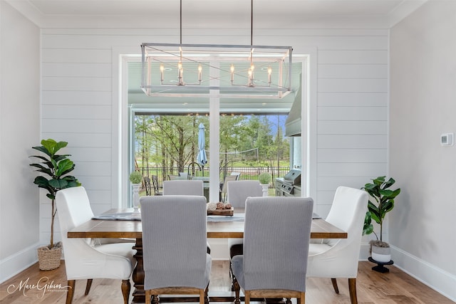 dining area featuring hardwood / wood-style flooring, a notable chandelier, and wood walls