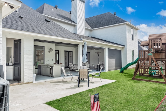 back of house featuring an outdoor kitchen, central air condition unit, a lawn, a playground, and a patio