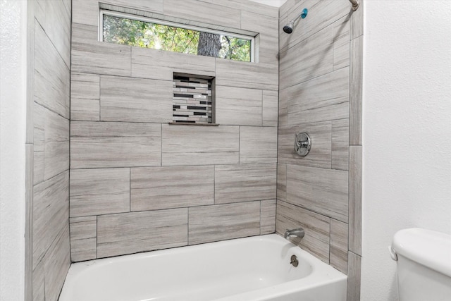 bathroom with toilet and tiled shower / bath