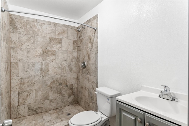 bathroom with toilet, vanity, and tiled shower