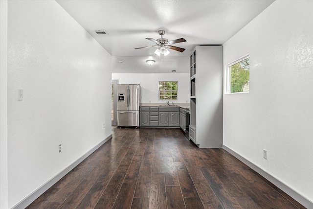 unfurnished living room with dark wood-type flooring, ceiling fan, and sink