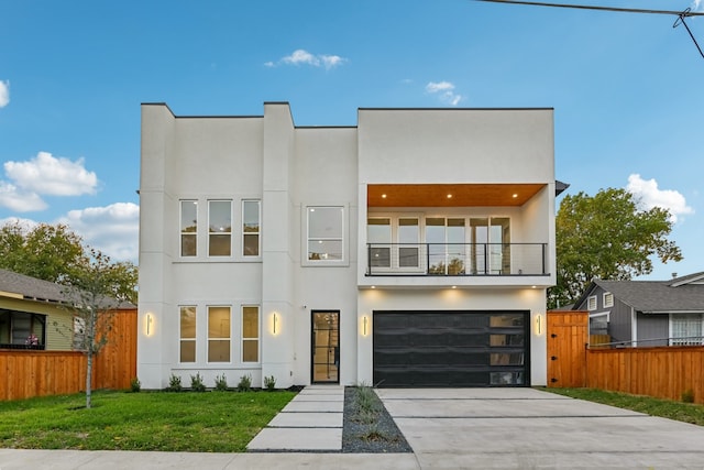 contemporary home with a front yard, a garage, and a balcony