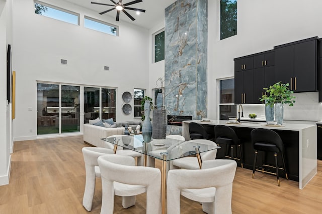 dining space with a towering ceiling, ceiling fan, and light hardwood / wood-style floors