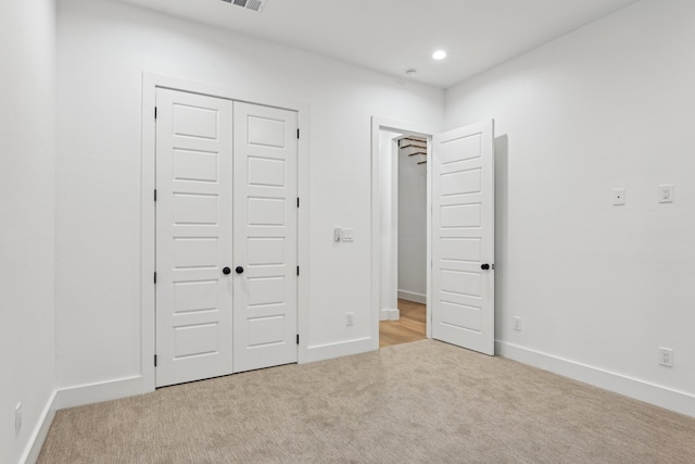 unfurnished bedroom with a closet and light colored carpet