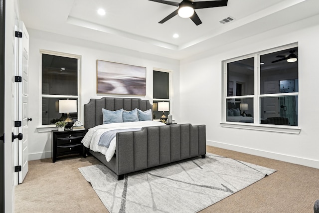 carpeted bedroom with ceiling fan and a tray ceiling