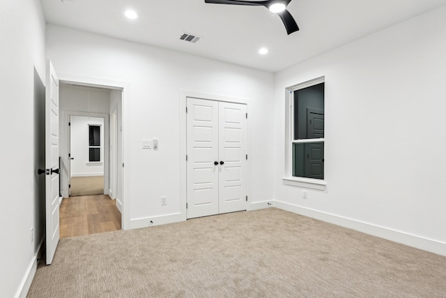 unfurnished bedroom with a closet, ceiling fan, and light carpet