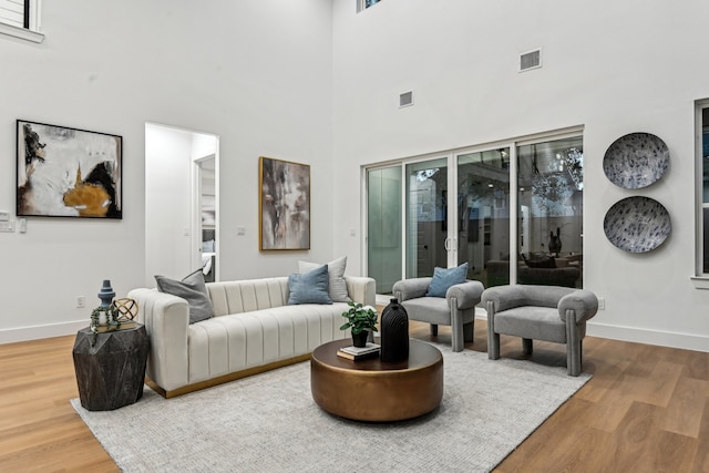 living room with a towering ceiling and hardwood / wood-style floors