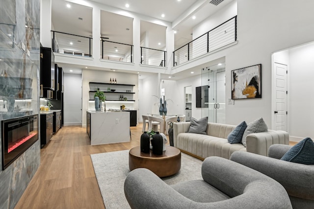 living room featuring light wood-type flooring and a towering ceiling