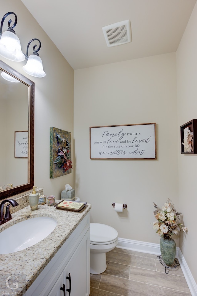 bathroom featuring vanity, toilet, and hardwood / wood-style flooring