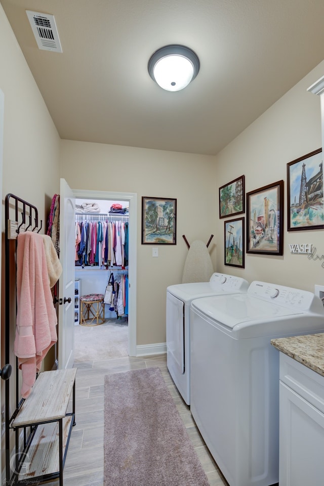 clothes washing area featuring independent washer and dryer, cabinets, and light hardwood / wood-style floors