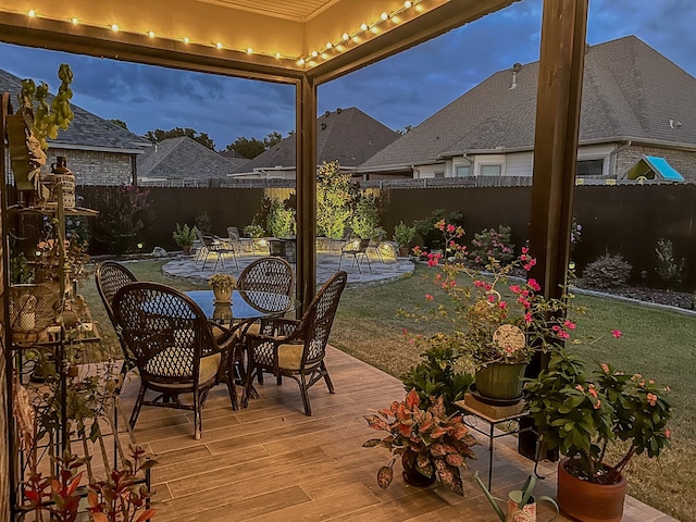 patio terrace at dusk with a deck and a lawn