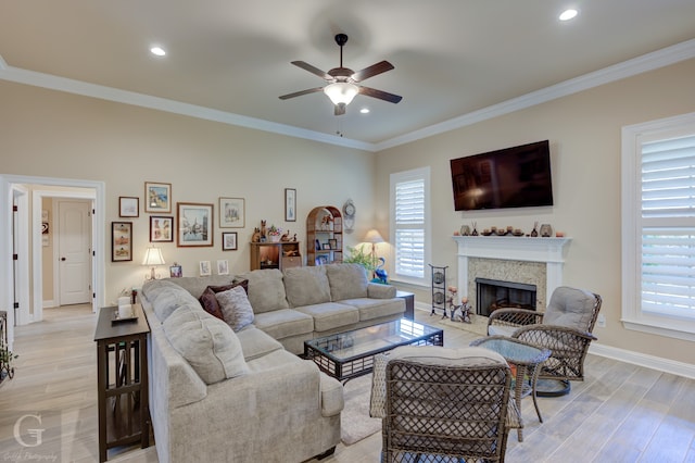 living room with ceiling fan, ornamental molding, a premium fireplace, and light hardwood / wood-style floors