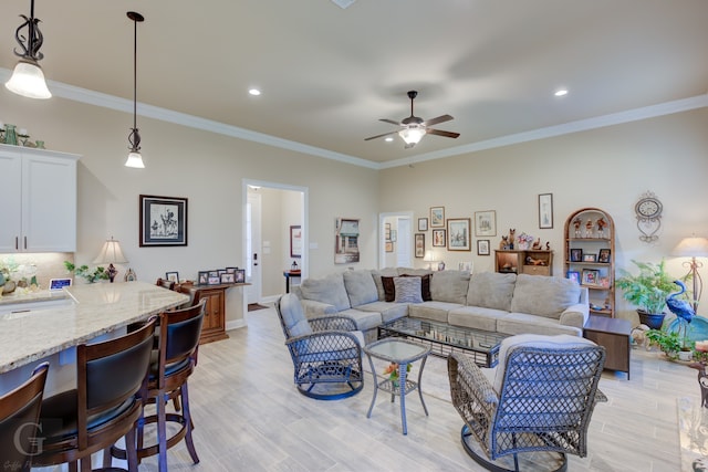 living room with crown molding, ceiling fan, and light wood-type flooring