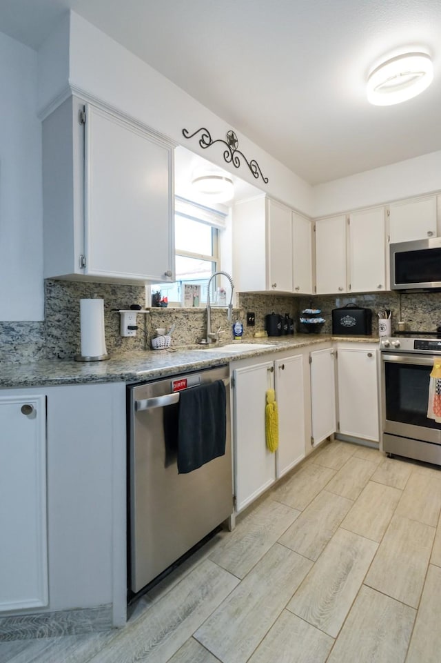 2725 S 40th St, Abilene, TX 79605 - kitchen with decorative backsplash, white cabinetry, a sink, light wood-style flooring, and appliances with stainless steel finishes