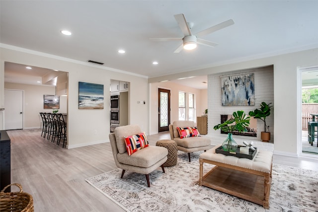 living room featuring light wood-type flooring, a wealth of natural light, ornamental molding, and ceiling fan