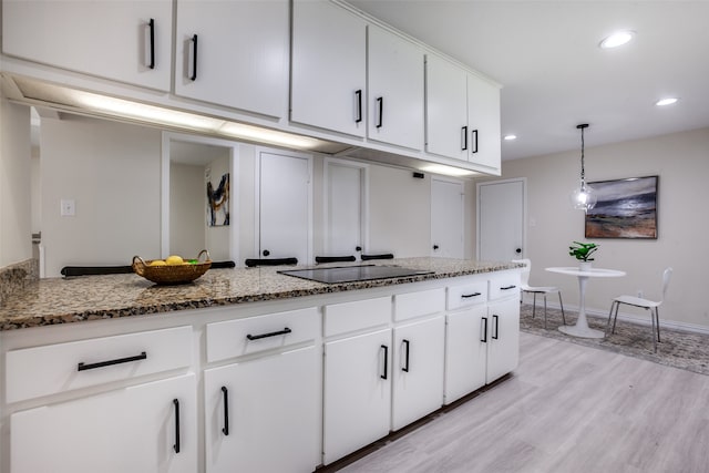 kitchen with white cabinets, light hardwood / wood-style floors, hanging light fixtures, and black electric cooktop