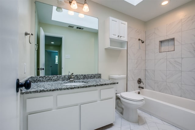 full bathroom with tile patterned flooring, vanity, tiled shower / bath combo, and toilet