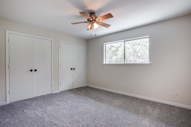 unfurnished bedroom featuring multiple closets, ceiling fan, and carpet