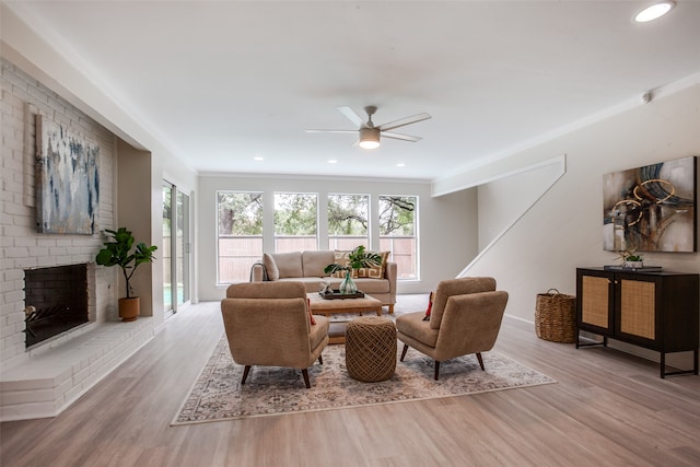 living room featuring a fireplace, light hardwood / wood-style floors, and ceiling fan