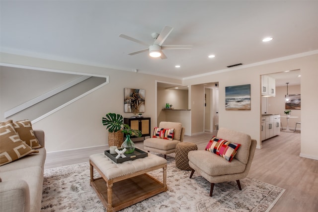 living room with ceiling fan, light wood-type flooring, and ornamental molding