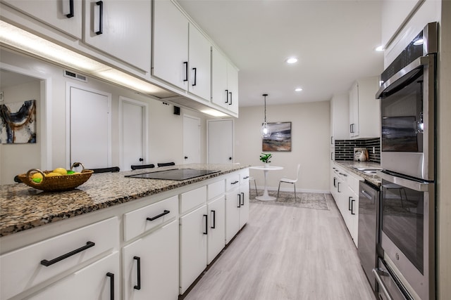 kitchen with white cabinets, pendant lighting, light wood-type flooring, and black electric cooktop