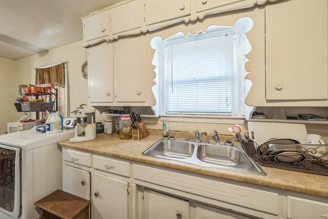 kitchen featuring washer / dryer, sink, and white cabinets